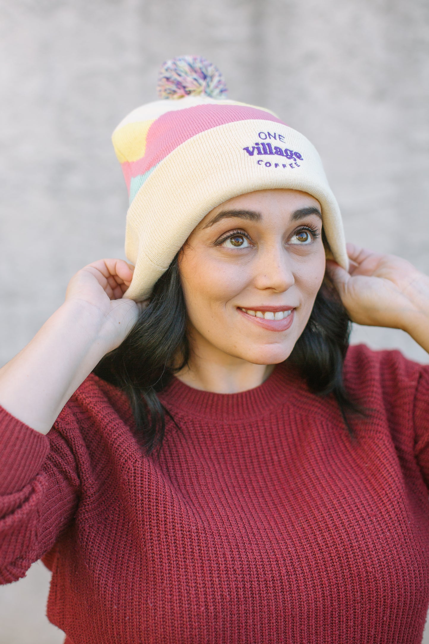 Image of a woman putting on a knit beanie.