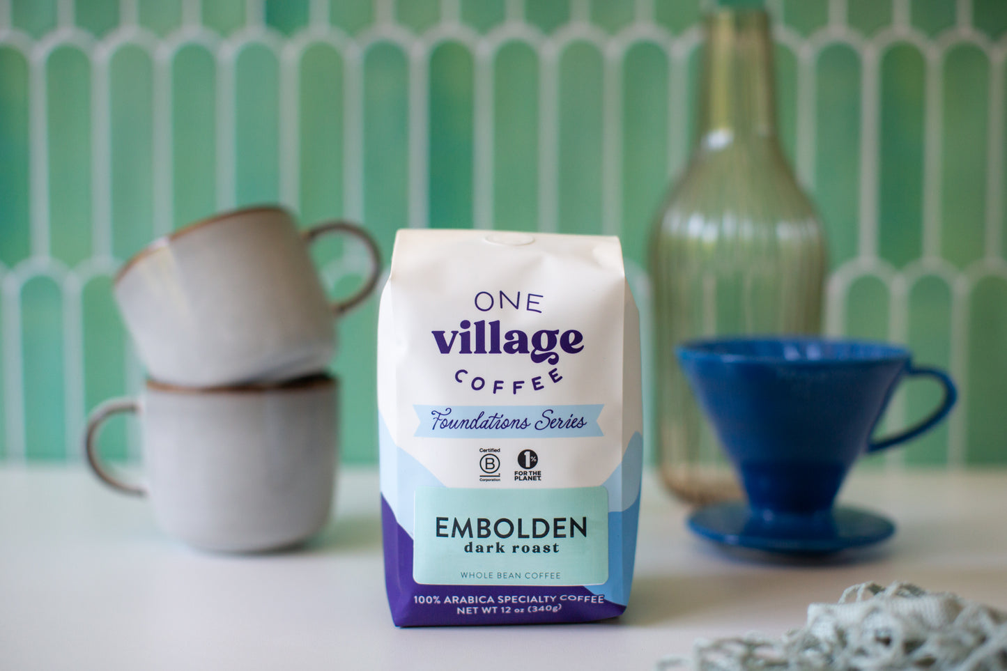 Image of Embolden dark roast coffee bag surrounded by mugs and pour over in kitchen.